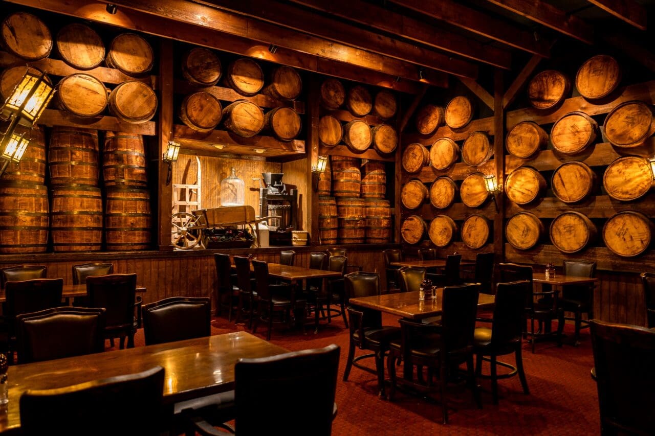 an image of a steakhouse with dozens of wine barrels hanging on the wall 