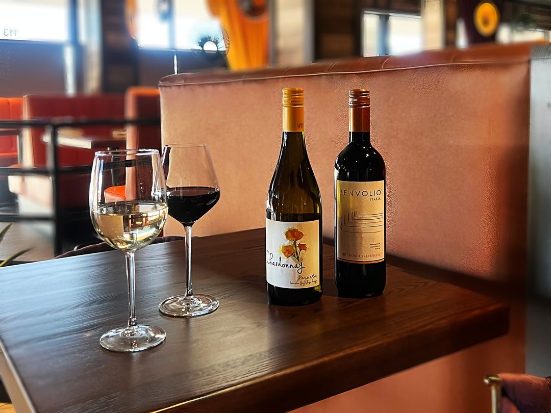 two bottles of wine and two glasses of wine on a table at an Italian restaurant. 