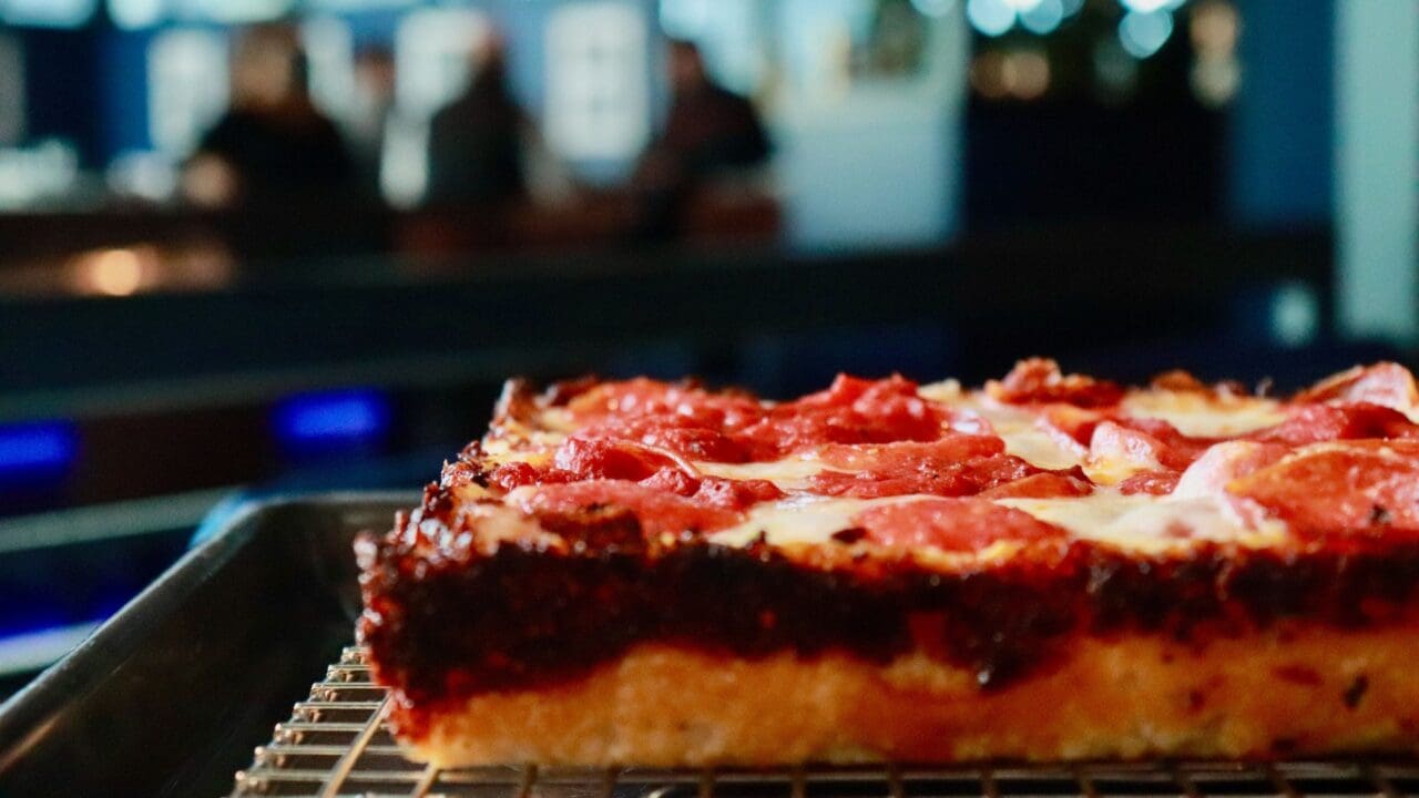 a picture of a peperoni Detroit Deep Dish style pizza on a wire rack.