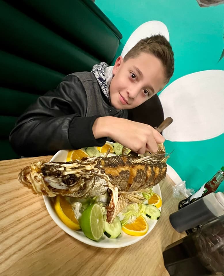 a young man sitting at a table with traditional mexican seafood on a plate