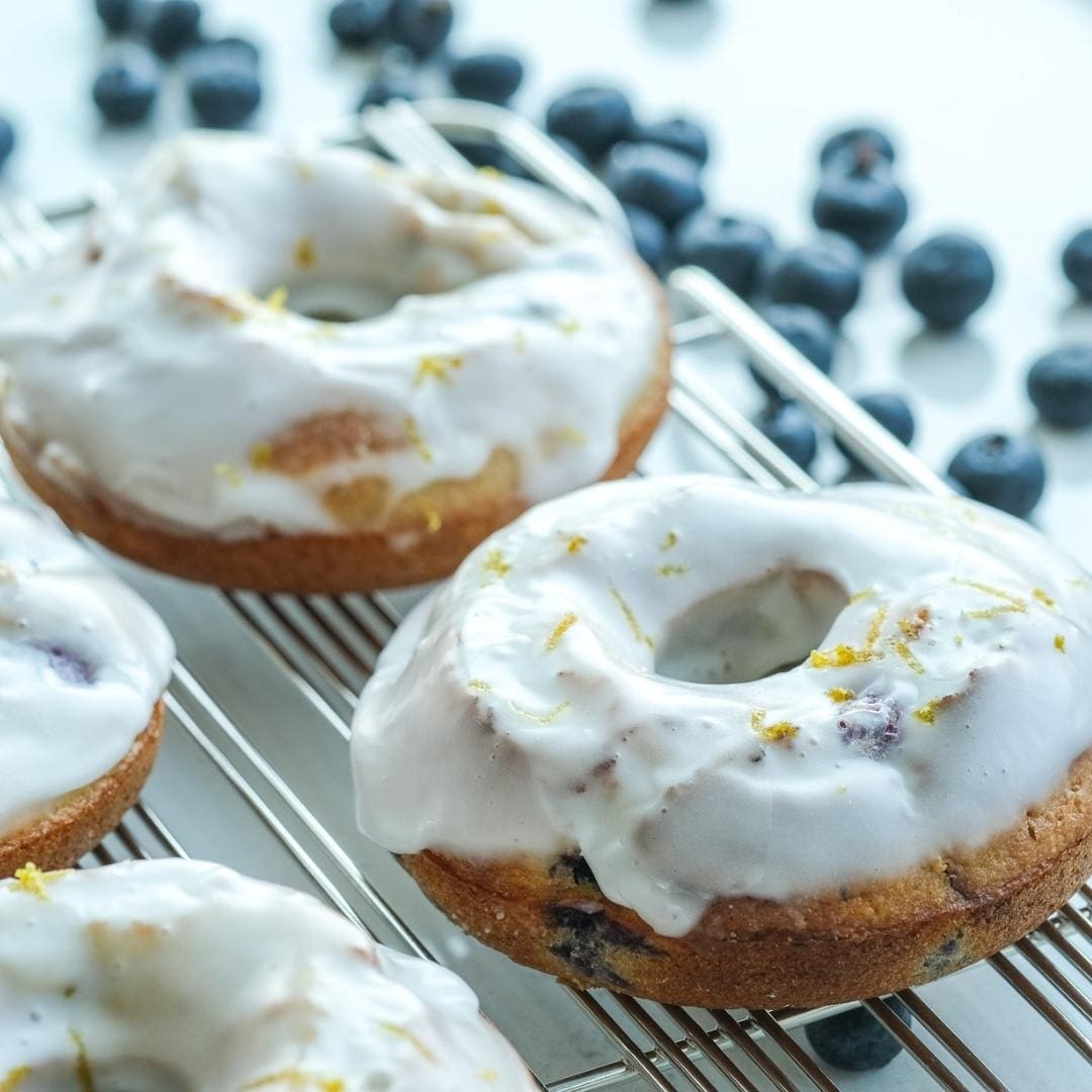 a tray of caked donuts with vanilla and blueberry icing