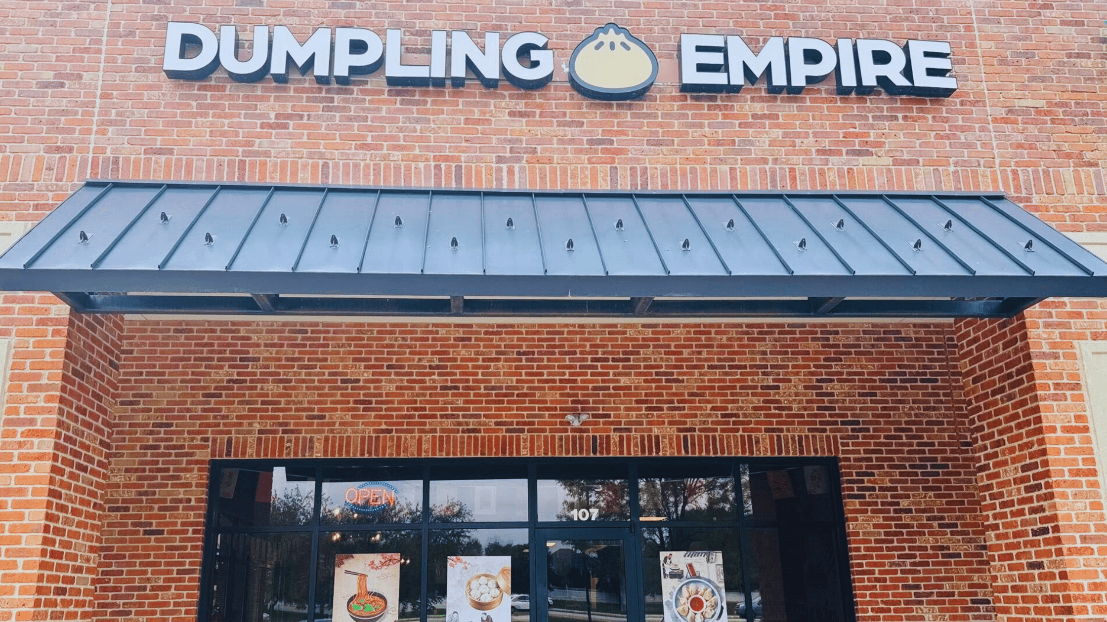 Front entrance of Dumpling Empire's new location on West Maple Road in Omaha, Nebraska, featuring brick facade and bold signage.
