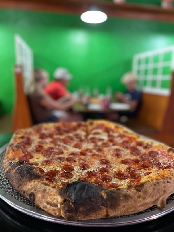 a picture of a pizza on a metal tray in a pizzeria 