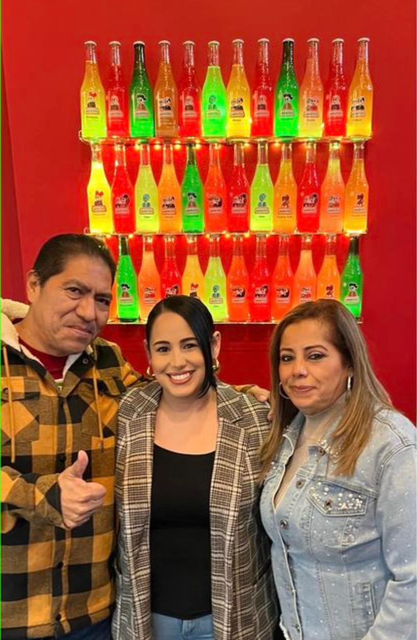 a man and two women standing in front of lit up jaritos bottles.